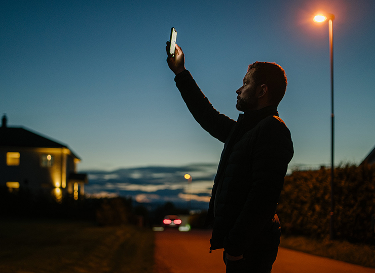 A man holding up a mobile phone, serching for signal